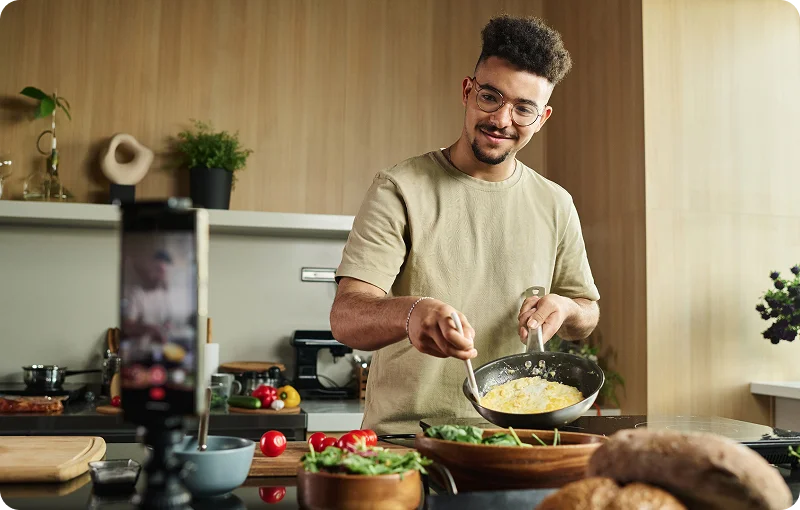 @lang('Jovem a cozinhar e a criar conteúdo num ambiente descontraído, símbolo da liberdade conquistada com o crédito habitação jovem 100% financiado.')